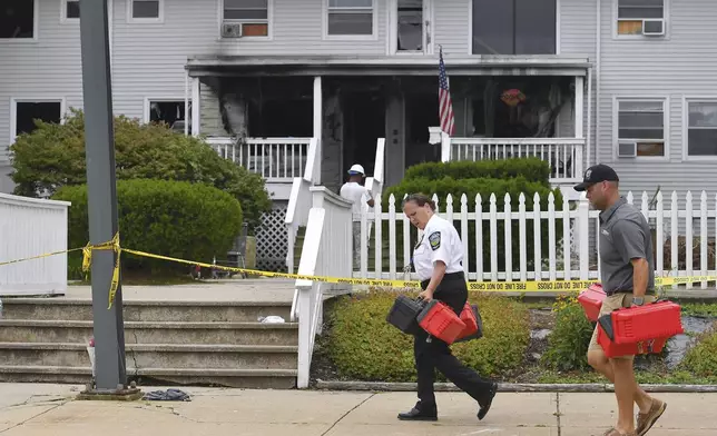 Investigators, front, remove boxes containing patient medications from the Gabriel House assisted living facility, behind, following a fire that resulted in multiple fatalities, in Fall River, Mass., Monday, July 14, 2025. (AP Photo/Steven Senne)