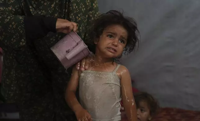 Rida Abu Hadayed, 32, cools off with water her 2-year-old daughter Azhar in their tent at a camp for displaced people in Khan Younis, southern Gaza Strip, Tuesday, July 1, 2025. (AP Photo/Abdel Kareem Hana)
