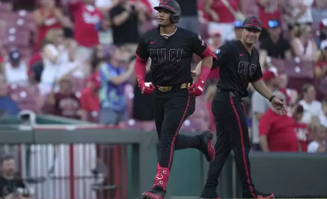 Cincinnati Reds' Noelvi Marte rounds third base as third base coach J.R. House, right, looks on after hitting a solo home run during the third inning of a baseball game against the Colorado Rockies in Cincinnati, Friday, July 11, 2025. (AP Photo/Carolyn Kaster)
