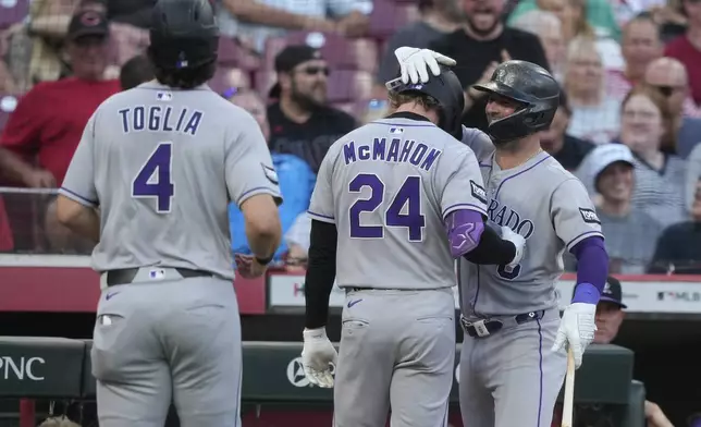 Colorado Rockies' Ryan McMahon, center, celebrates hitting a two-run homer with Kyle Farmer, right, during the fourth inning of a baseball game against the Cincinnati Reds in Cincinnati, Friday, July 11, 2025. Colorado Rockies first baseman Michael Toglia, left also scored. (AP Photo/Carolyn Kaster)