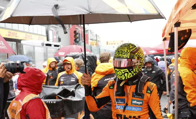 McLaren driver Lando Norris of Britain walks with an umbrella during the Formula One Grand Prix at the Spa-Francorchamps racetrack in Spa, Belgium, Sunday, July 27, 2025. (AP Photo/Geert Vanden Wijngaert)