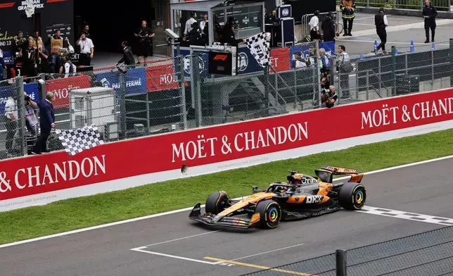 The checkered flag is waved as McLaren driver Oscar Piastri of Australia crosses the finish line to win the Formula One Grand Prix at the Spa-Francorchamps racetrack in Spa, Belgium, Sunday, July 27, 2025. (AP Photo/Geert Vanden Wijngaert)