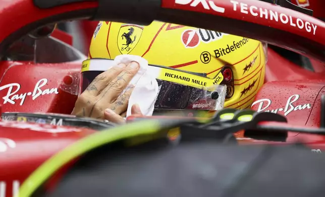 Ferrari driver Lewis Hamilton of Britain wipes rain off his face visor prior to the start of the Formula One Grand Prix at the Spa-Francorchamps racetrack in Spa, Belgium, Sunday, July 27, 2025. (Yves Herman, Pool Photo via AP)
