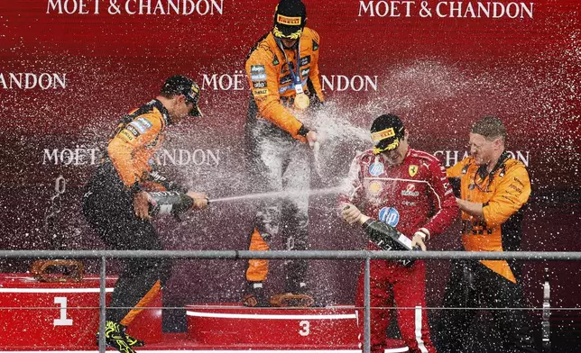 First place, McLaren driver Oscar Piastri of Australia, center, celebrates on the podium with second place McLaren driver Lando Norris of Britain, left, and third place Ferrari driver Charles Leclerc of Monaco, second right, during the Formula One Grand Prix at the Spa-Francorchamps racetrack in Spa, Belgium, Sunday, July 27, 2025. (AP Photo/Geert Vanden Wijngaert)