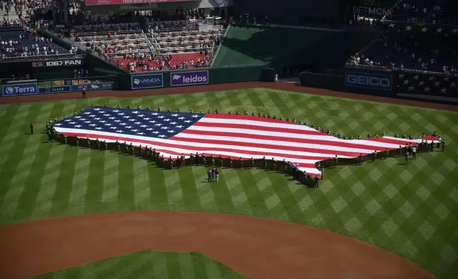 An American flag in the shape of the continental United States is displayed on the field before a baseball game between the Washington Nationals and the Boston Red Sox, Friday, July 4, 2025, in Washington. (AP Photo/Nick Wass)