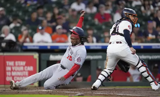 Washington Nationals' Josh Bell (19) slides across home plate as Houston Astros catcher Yainer Diaz waits for the throw during the second inning of a baseball game Wednesday, July 30, 2025, in Houston. (AP Photo/David J. Phillip)