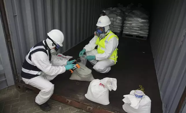 Customs workers test a sample of mercury hidden in gravel-filled bags in Lima, Peru, Wednesday, July 16, 2025. (AP Photo/Guadalupe Pardo)