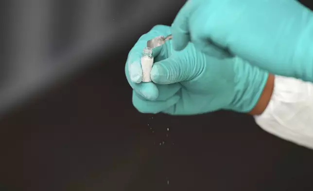 A costums worker shows a sample of mercury that was hidden in gravel-filled bags in Lima, Peru, Wednesday, July 16, 2025. (AP Photo/Guadalupe Pardo)
