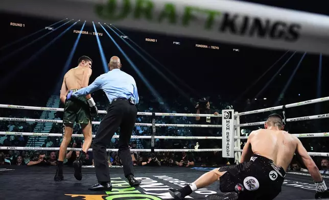 Tim Tszyu, right, reacts after being knocked down by Sebastian Fundora, left, in a super welterweight title boxing match Saturday, July 19, 2025, in Las Vegas. (AP Photo/John Locher)