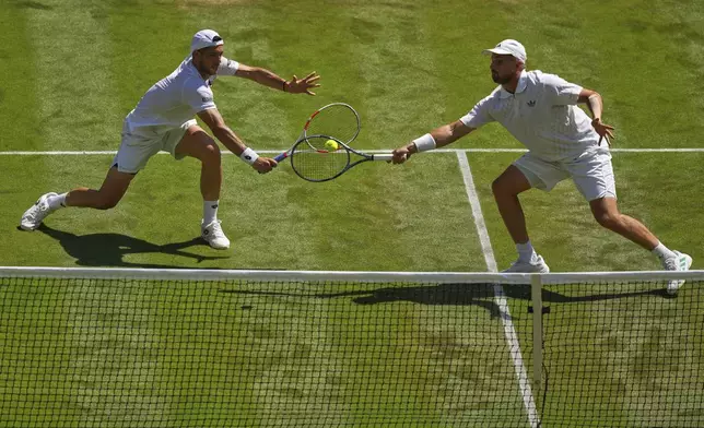 Julian Cash of Britain, left, and Lloyd Glasspool of Britain return the ball during the men's doubles final match against Rinky Hijikata of Australia and David Pel of the Netherlands at the Wimbledon Tennis Championships in London, Saturday, July 12, 2025.(AP Photo/Joanna Chan)