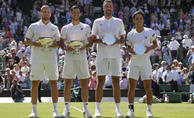 Lloyd Glasspool of Britain, left, and Julian Cash of Britain celebrate after winning the men's doubles final match against Rinky Hijikata of Australia, right, and David Pel of the Netherlands at the Wimbledon Tennis Championships in London, Saturday, July 12, 2025. (AP Photo/Kin Cheung)