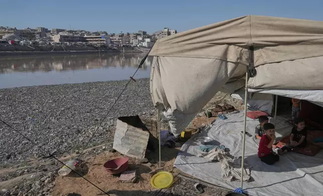 Children sit in their tent at a camp for displaced Palestinians, located near a rainwater collection reservoir that has been contaminated by sewage and garbage following the Israeli air and ground operations in Gaza City, Friday, July 18, 2025. (AP Photo/Jehad Alshrafi)