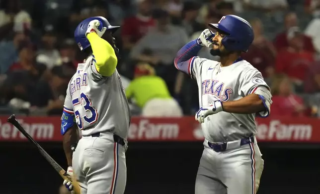 Texas Rangers' Marcus Semien, right, is congratulated by Adolis Garcia after hitting a two-run home run during the seventh inning of a baseball game against the Los Angeles Angels, Wednesday, July 9, 2025 in Anaheim, Calif. (AP Photo/Mark J. Terrill)