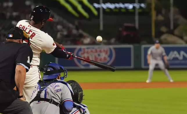 Los Angeles Angels' Jorge Soler, center, hits a two-run home run as Texas Rangers catcher Kyle Higashioka watches during the eighth inning of a baseball game Wednesday, July 9, 2025 in Anaheim, Calif. (AP Photo/Mark J. Terrill)