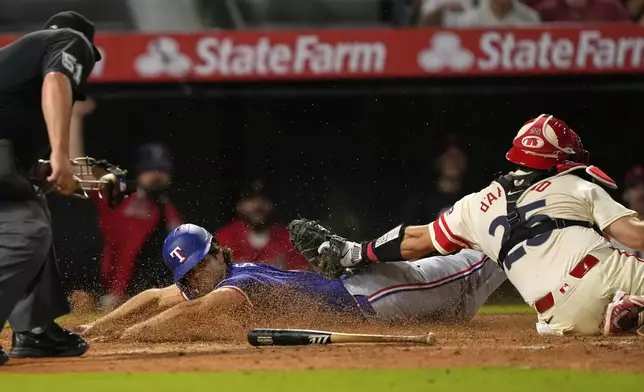 Texas Rangers' Josh Smith, center, scores on a single by Ezequiel Duran as Los Angeles Angels catcher Travis d'Arnaud puts a late tag on him during the sixth inning of a baseball game Tuesday, July 29, 2025, in Anaheim, Calif. (AP Photo/Mark J. Terrill)