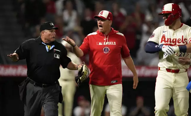 Los Angeles Angels interim manager Ray Montgomery, center, yells toward the Texas Rangers bench as home plate umpire Marvin Hudson gestures after Mike Trout, right, was hit by a pitch during the eighth inning of a baseball game Tuesday, July 29, 2025, in Anaheim, Calif. (AP Photo/Mark J. Terrill)