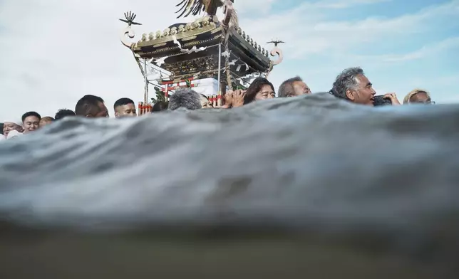 Participants carry a portable shrine, or mikoshi, into the sea during a purification rite at the annual Kurihama Sumiyoshi Shrine Festival at Kurihama, Yokosuka city, south of Tokyo Sunday, July 27, 2025. (AP Photo/Eugene Hoshiko)