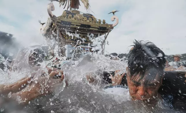 Participants carry a portable shrine, or mikoshi, into the sea during a purification rite at the annual Kurihama Sumiyoshi Shrine Festival at Kurihama, Yokosuka city, south of Tokyo Sunday, July 27, 2025. (AP Photo/Eugene Hoshiko)