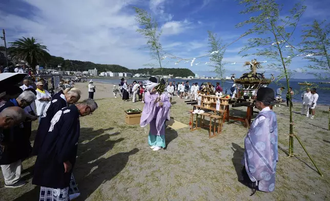 Shinto priests perform a ritual for participants before they carry a portable shrine, or mikoshi, into the sea during a purification rite at the annual Kurihama Sumiyoshi Shrine Festival at Kurihama, Yokosuka city, south of Tokyo Sunday, July 27, 2025. (AP Photo/Eugene Hoshiko)