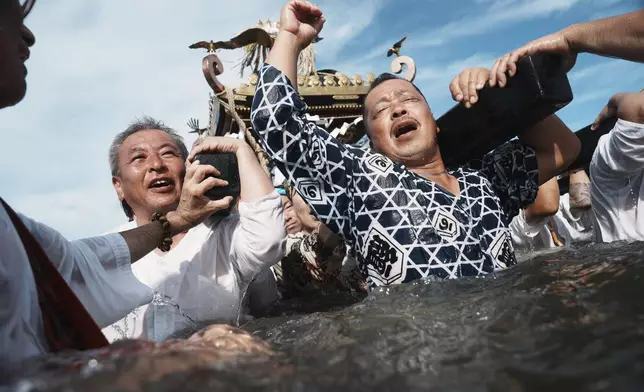 Participants carry a portable shrine, or mikoshi, into the sea during a purification rite at the annual Kurihama Sumiyoshi Shrine Festival at Kurihama, Yokosuka city, south of Tokyo Sunday, July 27, 2025. (AP Photo/Eugene Hoshiko)