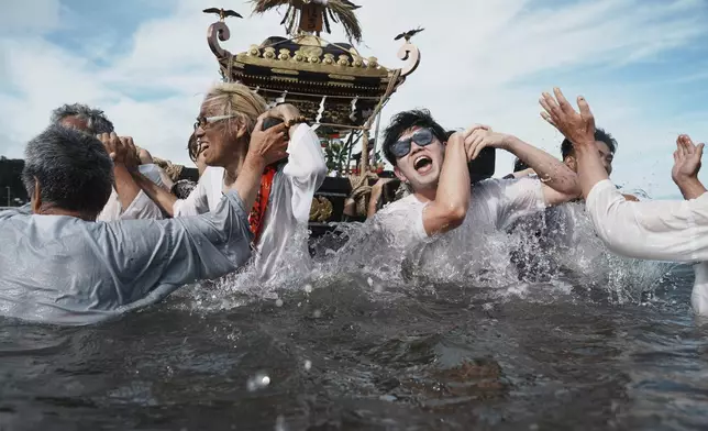 Participants carry a portable shrine, or mikoshi, into the sea during a purification rite at the annual Kurihama Sumiyoshi Shrine Festival at Kurihama, Yokosuka city, south of Tokyo Sunday, July 27, 2025. (AP Photo/Eugene Hoshiko)