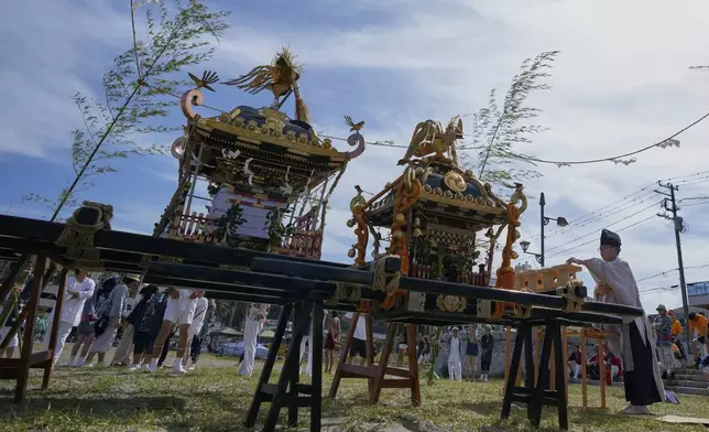 Shinto priests perform a ritual for participants before they carry a portable shrine, or mikoshi, into the sea during a purification rite at the annual Kurihama Sumiyoshi Shrine Festival at Kurihama, Yokosuka city, south of Tokyo Sunday, July 27, 2025. (AP Photo/Eugene Hoshiko)