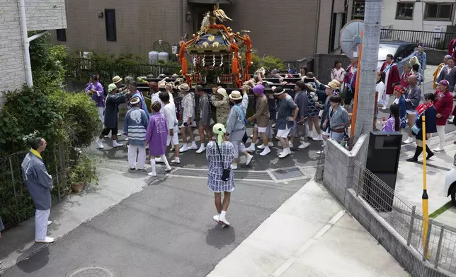 Participants carry a portable shrine, or mikoshi, along a narrow alley during a purification rite at the annual Kurihama Sumiyoshi Shrine Festival at Kurihama, Yokosuka city, south of Tokyo Sunday, July 27, 2025. (AP Photo/Eugene Hoshiko)
