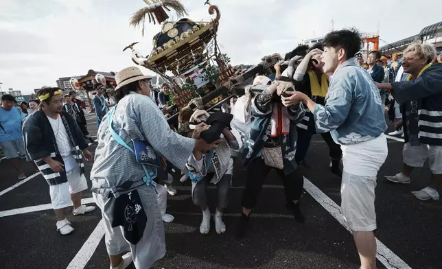 Participants carry a portable shrine, or mikoshi, during the annual Kurihama Sumiyoshi Shrine Festival at Kurihama, Yokosuka city, south of Tokyo Sunday, July 27, 2025. (AP Photo/Eugene Hoshiko)