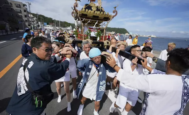 Participants carry a portable shrine, or mikoshi, and proceed towards the sea during a purification rite at the annual Kurihama Sumiyoshi Shrine Festival at Kurihama, Yokosuka city, south of Tokyo Sunday, July 27, 2025. (AP Photo/Eugene Hoshiko)