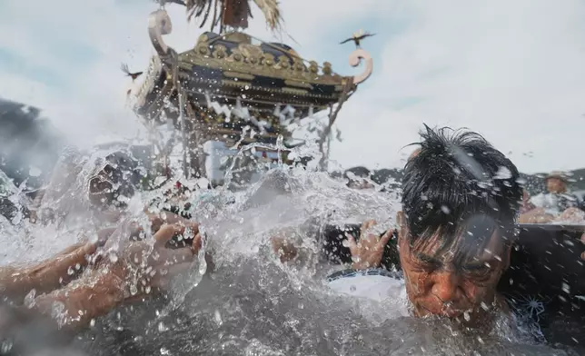 HOLD- Participants carry a portable shrine, or mikoshi, into the sea during a purification rite at the annual Kurihama Sumiyoshi Shrine Festival at Kurihama, Yokosuka city, south of Tokyo Sunday, July 27, 2025. (AP Photo/Eugene Hoshiko)
