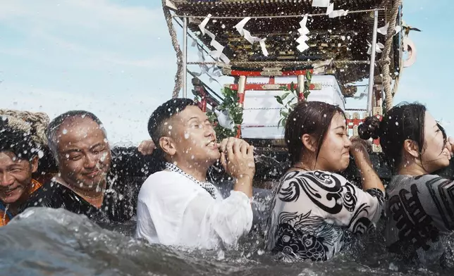 Participants carry a portable shrine, or mikoshi, into the sea during a purification rite at the annual Kurihama Sumiyoshi Shrine Festival at Kurihama, Yokosuka city, south of Tokyo Sunday, July 27, 2025. (AP Photo/Eugene Hoshiko)