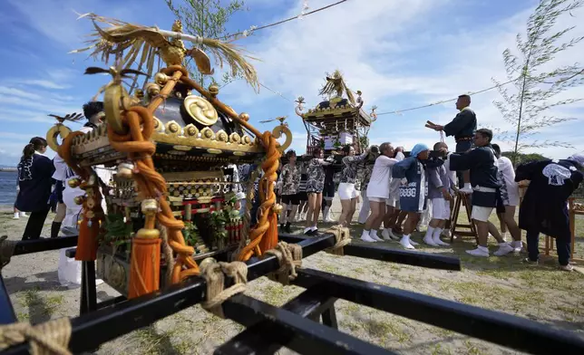 Participants carry a portable shrine, or mikoshi, before they proceed into the sea during a purification rite at the annual Kurihama Sumiyoshi Shrine Festival at Kurihama, Yokosuka city, south of Tokyo Sunday, July 27, 2025. (AP Photo/Eugene Hoshiko)