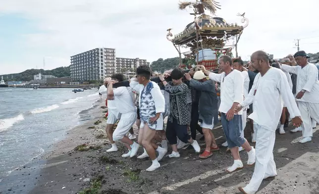 Participants carry a portable shrine, or mikoshi, into the sea during a purification rite at the annual Kurihama Sumiyoshi Shrine Festival at Kurihama, Yokosuka city, south of Tokyo Sunday, July 27, 2025. (AP Photo/Eugene Hoshiko)