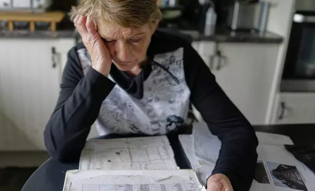 Catherine Corless, who revealed that remains of nearly 800 dead infants from a mother and baby home in Tuam, Ireland, were unaccounted for and likely buried in a mass grave, reviews her records at her home outside Tuam on Tuesday, July 8, 2025. (AP Photo/Brian Melley)