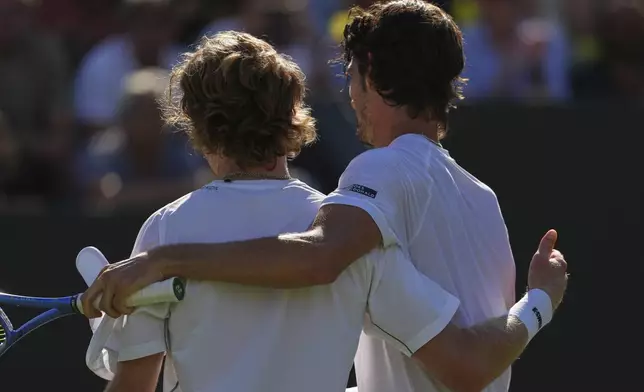 Andrey Rublev of Russia, left, embraces Lloyd Harris of South Africa at the net after winning their second round men's singles match at the Wimbledon Tennis Championships in London, Wednesday, July 2, 2025. (AP Photo/Joanna Chan)