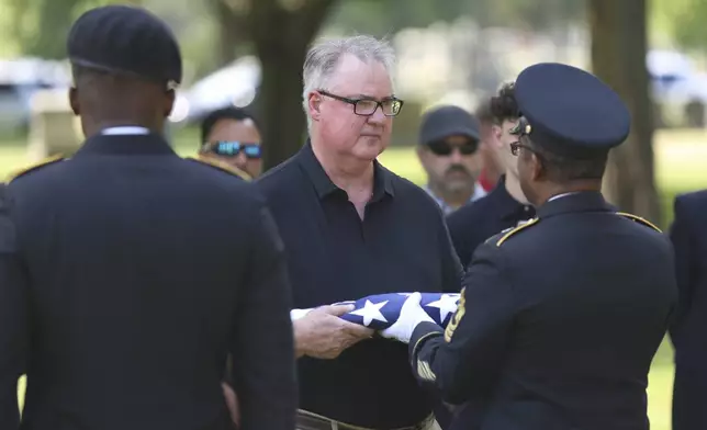 Staff Sgt. Kobe Green and Master Sgt. Derrick Bailey, right, present Mark Bailey with an American flag during during a military funeral for his aunt, 75-year-old Pfc. Reba C. Bailey, a former missing person cold case named Seven Doe, Tuesday, July 1, 2025 at Mount Olivet Catholic Cemetery in Chicago. (AP Photo/Talia Sprague)