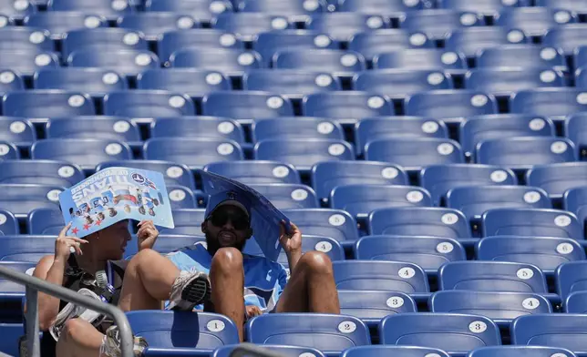 Tennessee Titans fans cover their heads in the heat during "Back Together Weekend" at the team's NFL football training camp Saturday, July 26, 2025, in Nashville, Tenn. (AP Photo/George Walker IV)