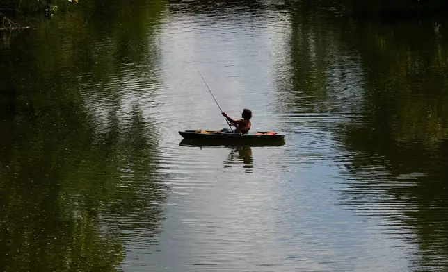 A person kayaks along the Stones River during a heat advisory, Friday, July 25, 2025, in Murfreesboro, Tenn. (AP Photo/George Walker IV)