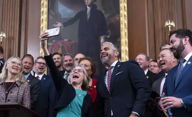 Rep. Mariannette Miller-Meeks, R-Iowa, center left, holds up her phone to snap a picture with Rep. Juan Ciscomani, R-Ariz., center right, as Republicans in the House celebrate final passage of President Donald Trump's signature bill of tax breaks and spending cuts, at the Capitol in Washington, Thursday, July 3, 2025. (AP Photo/J. Scott Applewhite)