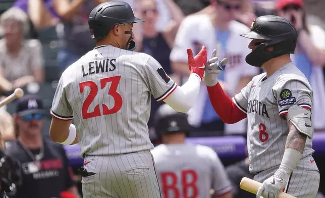 Minnesota Twins' Christian Vázquez, right, congratulates Royce Lewis (23) after Lewis' solo home run off Colorado Rockies relief pitcher Ryan Rolison in the fourth inning of a baseball game Sunday, July 20, 2025, in Denver. (AP Photo/David Zalubowski)
