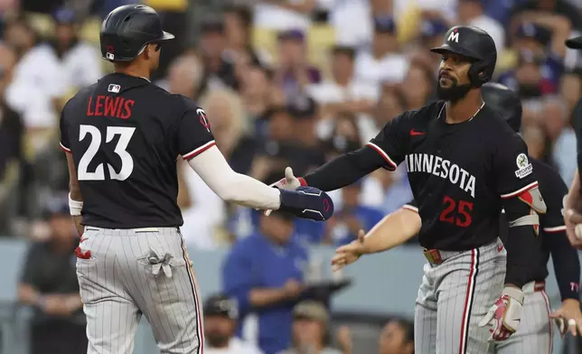 Minnesota Twins' Royce Lewis (23) is greeted by teammate Byron Buxton after scoring off a two-RBI double by Christian Vazquez during the second inning of a baseball game against the Los Angeles Dodgers Tuesday, July 22, 2025, in Los Angeles. (AP Photo/Eric Thayer)