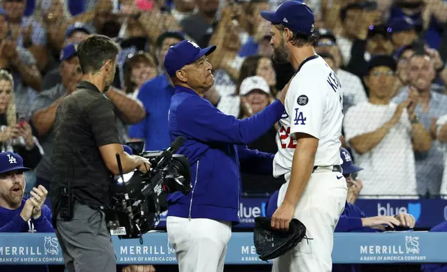 Los Angeles Dodgers pitcher Clayton Kershaw, right, is congratulated by Dodgers manager Dave Roberts, center, after recording his 3,000th career strikeout during the sixth inning of a baseball game against Chicago White Sox Wednesday, July 2, 2025, in Los Angeles. (AP Photo/Kevork Djansezian)