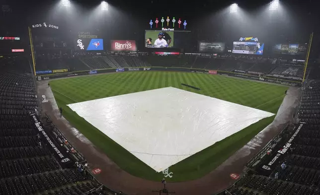 A tarp covers the infield during a rain delay in the seventh inning of a baseball game between the Toronto Blue Jays and the Chicago White Sox in Chicago, Tuesday, July 8, 2025. (AP Photo/Nam Y. Huh)