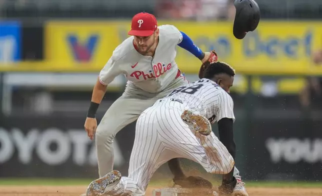 Philadelphia Phillies shortstop Trea Turner (7), left, can't catch Chicago White Sox's Luis Robert Jr. (88) as he steals second during the sixth inning of a baseball game Wednesday, July 30, 2025, in Chicago. (AP Photo/Erin Hooley)
