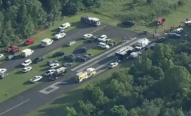 This image taken from video provided by WPVI-TV/6ABC shows emergency personnel working at the scene where a small skydiving aircraft went off the end of a runway and crashed in the woods at Cross Keys Airport in Gloucester County, N.J., Wednesday, July 2, 2025. (WPVI-TV/6ABC via AP)