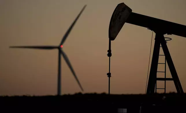 FILE - A pumpjack operates in the foreground while a wind turbine at the Buckeye Wind Energy wind farm rises in the distance, Sept. 30, 2024, near Hays, Kan. (AP Photo/Charlie Riedel, File)