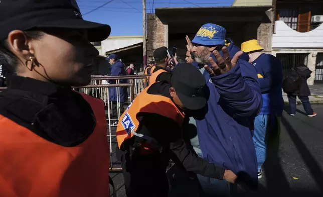 A police officer conducts an entry inspection on a Rosario Central soccer fan as he arrives for a soccer match in Buenos Aires, Saturday, July 19, 2025, after the soccer federation lifted a 12-year ban as a test run on away fans in Argentina’s local leagues. (AP Photo/Gustavo Garello)