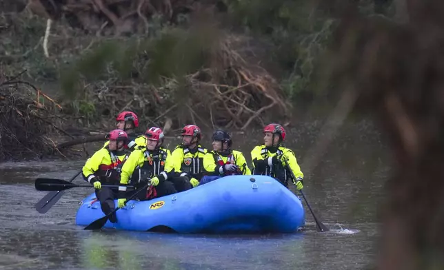 Officials ride a boat as they arrive to assist with a recovery effort at Camp Mystic along the Guadalupe River after a flash flood swept through the area Sunday, July 6, 2025, in Hunt, Texas. (AP Photo/Julio Cortez)