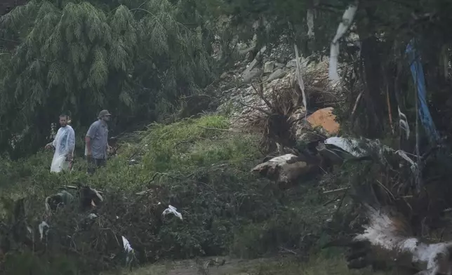 Men survey damage left by a raging Guadalupe River, Friday, July 4, 2025, in Kerrville, Texas. (AP Photo/Eric Gay)