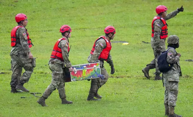 Military personnel carry a camp trunk salvaged down river from Camp Mystic along the Guadalupe River after a flash flood swept through the area Sunday, July 6, 2025, in Hunt, Texas. (AP Photo/Julio Cortez)